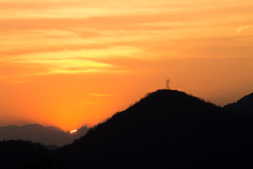 Outline of mountains at sunset with electric pylon
