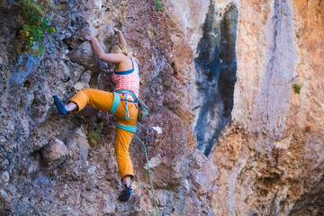 Fototapeta premium A girl climbs a rock.