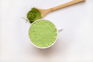 matcha latte in a cup and matcha powder in wooden spoon. healthy drinks concept. modern fashionable drink for weight loss and energy boost. top view