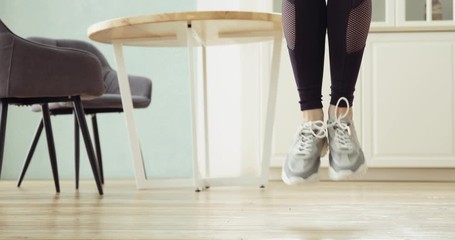 Legs of sporty woman is jumping rope making cardio training at home in kitchen. Girl is having personal aerobic workout in modern interior. Home fitness training and bodycare concept. Skipping rope. - Powered by Adobe