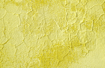 Fototapeta premium Fragment of old house wall close-up. Yellow background. Peeling plaster on concrete surface. Cracks in paint. tinted in yellow, warm colors backdrop. Copy space. Place for text. Selective focus image.
