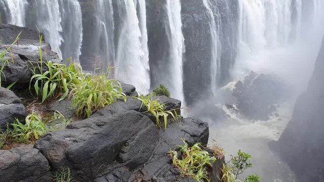 Victoria Falls at the Zambia Zimbabwe boarder with blue sky and white clouds and water cascading over the cliff.