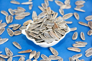 natural small sunflower seeds in a white plate on a blue background