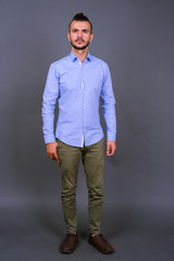 Full body shot of handsome bearded Turkish businessman thinking