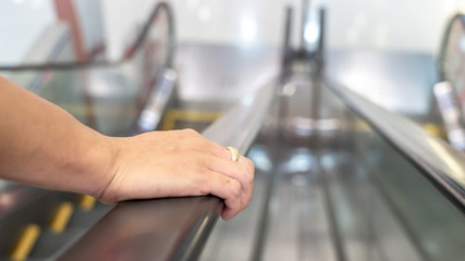 a hand of a man is touching an escalator in the supermarket, get a risk or spread virus or bacteria. Corona virus. Covid-19
