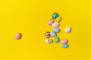 Different colorful Easter eggs on yellow background, top view. Holiday eggs