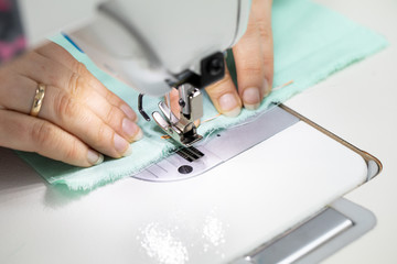 Obraz na płótnie Canvas Experienced seamstress sews fabric protective masks as standard during the COVID-19 epidemic.