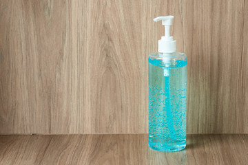 Blue hand sanitizer gel in clear pump bottle with wood background, that use for killing germs, bacteria and viruses. Prevent the spread of germs and bacteria and avoid infections corona virus.