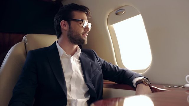 business smiling, touching suit, and resting while traveling by plane