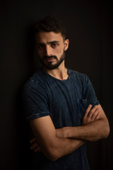 Portrait of young brunette Indian Kashmiri man in casual tee shirt in black copy space studio background. lifestyle and fashion.