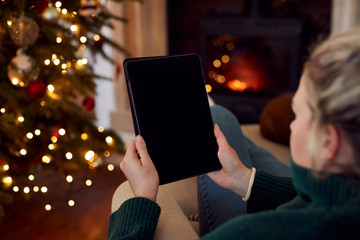 Woman At Home Using Digital Tablet With Blank Screen At Christmas