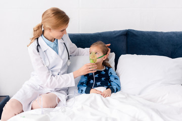 beautiful doctor in white coat touching respiratory mask on asthmatic child