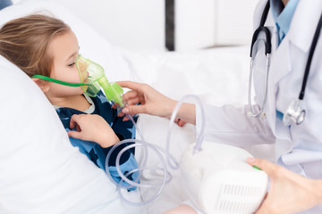 doctor touching respiratory mask on asthmatic kid using compressor inhaler