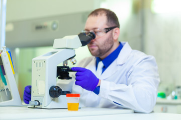Naklejka na ściany i meble Laboratory worker performing urinalysis using microscope and laboratory equipment in a medical laboratory
