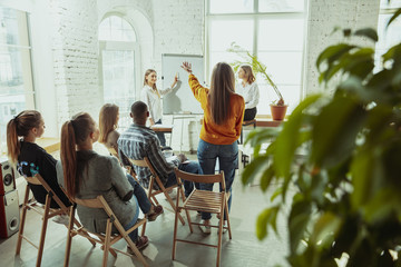 Asking a question. Female speaker giving presentation in hall at workshop. Business centre. Rear view of participants in audience. Conference event, training. Education, diversity, inclusive concept.