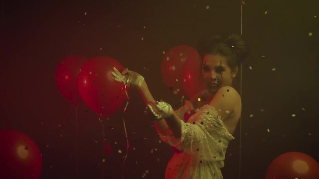 thick smoke Old film Style dark gothic. Animator woman crazy clown bursts blows up red helium balloon pops with needle, golden serpentine sparkles slowly falling. Joy positive emotions laughter 