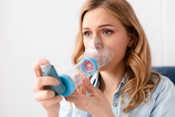 selective focus of asthmatic woman using inhaler with spacer - obrazy, fototapety, plakaty