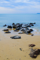 Beach in the sea with several black stones