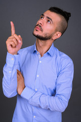 Portrait of handsome bearded Turkish businessman pointing up