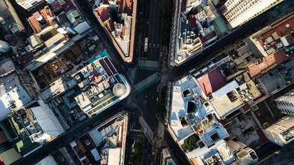 Aerial top down view on four way intersection in between tall buildings during golden hour (sunset...