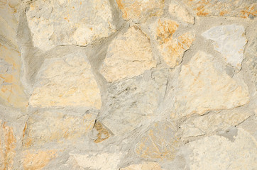 Light stone wall close-up. Brickwork of yellow, gray and orange stones and cement or concrete between them. Abstract urban backdrop. Copy space. Building background. Place for text.
Selective focus.