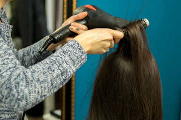 Obraz na płótnie Canvas Closeup hairdresser coiffeur makes hairstyle. No face in the scene.