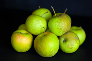 Fresh harvest of green apples on a black background, farm organic fruits