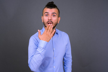 Portrait of handsome bearded Turkish businessman looking shocked