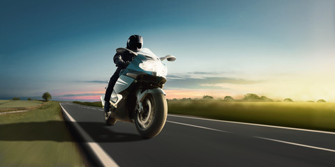Rapid motorbike ride on the country road at the most beautiful sunset. Adventure and motor sport.