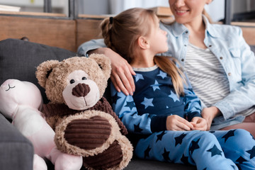 selective focus of soft toys near kid looking at happy mother