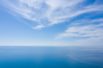 An aerial view of eternal blue sea or ocean with sunny and cloudy sky.