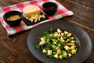 Arugula Salad with Pear on a black plate with ingredients