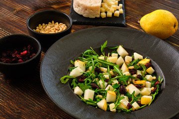 Arugula Salad with Pear on a black plate with ingredients