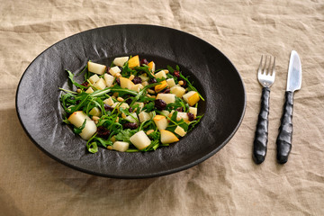 Arugula Salad with Pear on a black plate