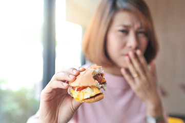 A girl was fulled after eating burger,Burger is hight calories food,Unpalatable food makes eating less,Selective focus