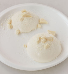 Delicious italian dessert panna cotta with milk chocolate on a plate on white background