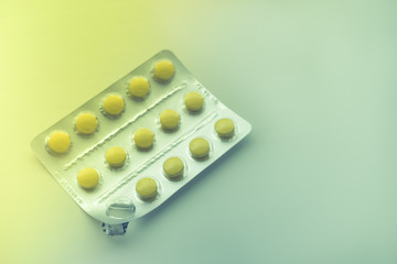 Blister with yellow vitamins on the table, one vitamin is already eaten, top view