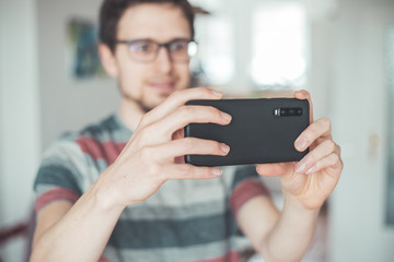 Social media content production with the smartphone. Close up of black smartphone camera lens indoors.