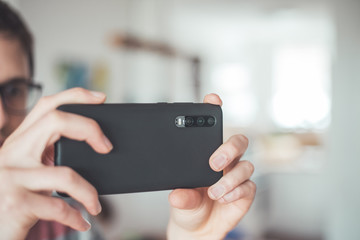 Social media content production with the smartphone. Close up of black smartphone camera lens indoors.