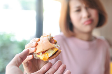 Cheese burger is heigh calories for dieting women,A woman refuses cheese burger because she is controlling her calories,Dieting,Selective focus