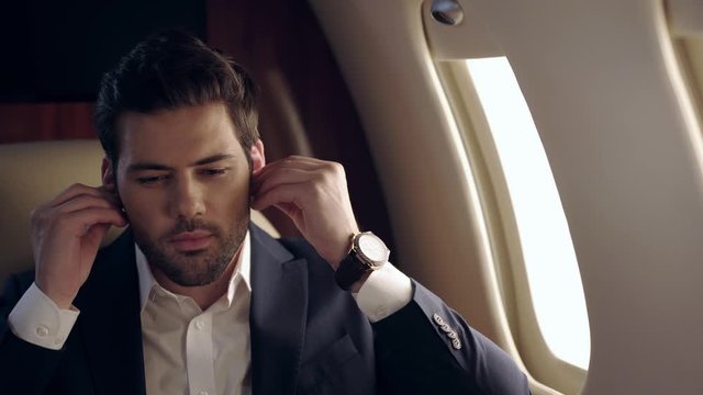happy businessman traveling by plane and listening music in wireless earphones