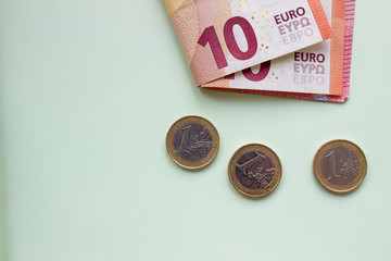 A bundle of Euro banknotes and coins on a light background