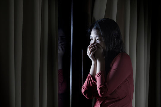 young beautiful scared and depressed Asian Chinese woman feeling overwhelmed and in panic lockdown alone at home during covid-19 virus outbreak quarantine