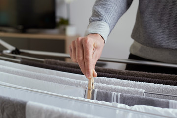 man hanging clothes on a drying rack