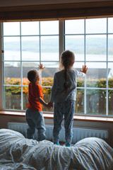 children holding hands and touching window