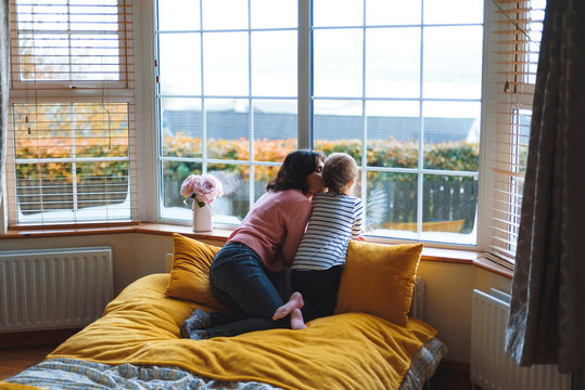 mother kissing daughter at home