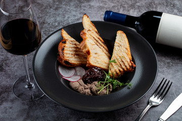 Chicken liver pate with toasted bread  and a glass of red wine on a stone table in a restaurant