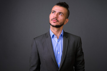 Portrait of handsome bearded Turkish businessman in suit thinking
