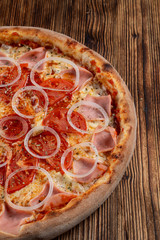 Close up of classic italian pizza with ham, onion rings and tomato, vertical, half of pizza
