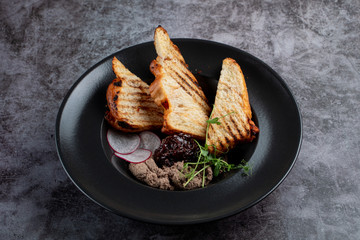 Close up of chicken liver pate and a glass of red wine on a stone table